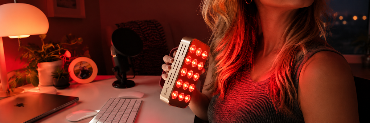 Person applying a red light therapy device to their face and jawline, illustrating skin support during weight loss