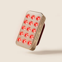 Halio RegenBoost handheld red light therapy panel with 15 glowing red LEDs and a metallic rose-gold finish.