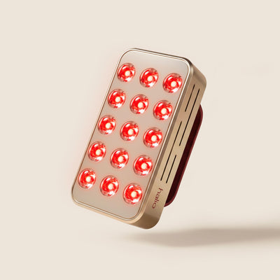 Halio RegenBoost handheld red light therapy panel with 15 glowing red LEDs and a metallic rose-gold finish.